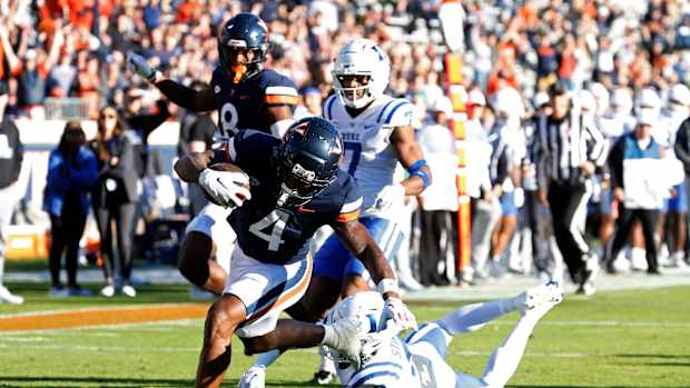 Nov 18, 2023; Charlottesville, Virginia, USA; Virginia Cavaliers wide receiver Malik Washington (4) scores a touchdown as Duke Blue Devils safety Jaylen Stinson (2) chases during the first quarter at Scott Stadium. Mandatory Credit: Geoff Burke-USA TODAY Sports  
